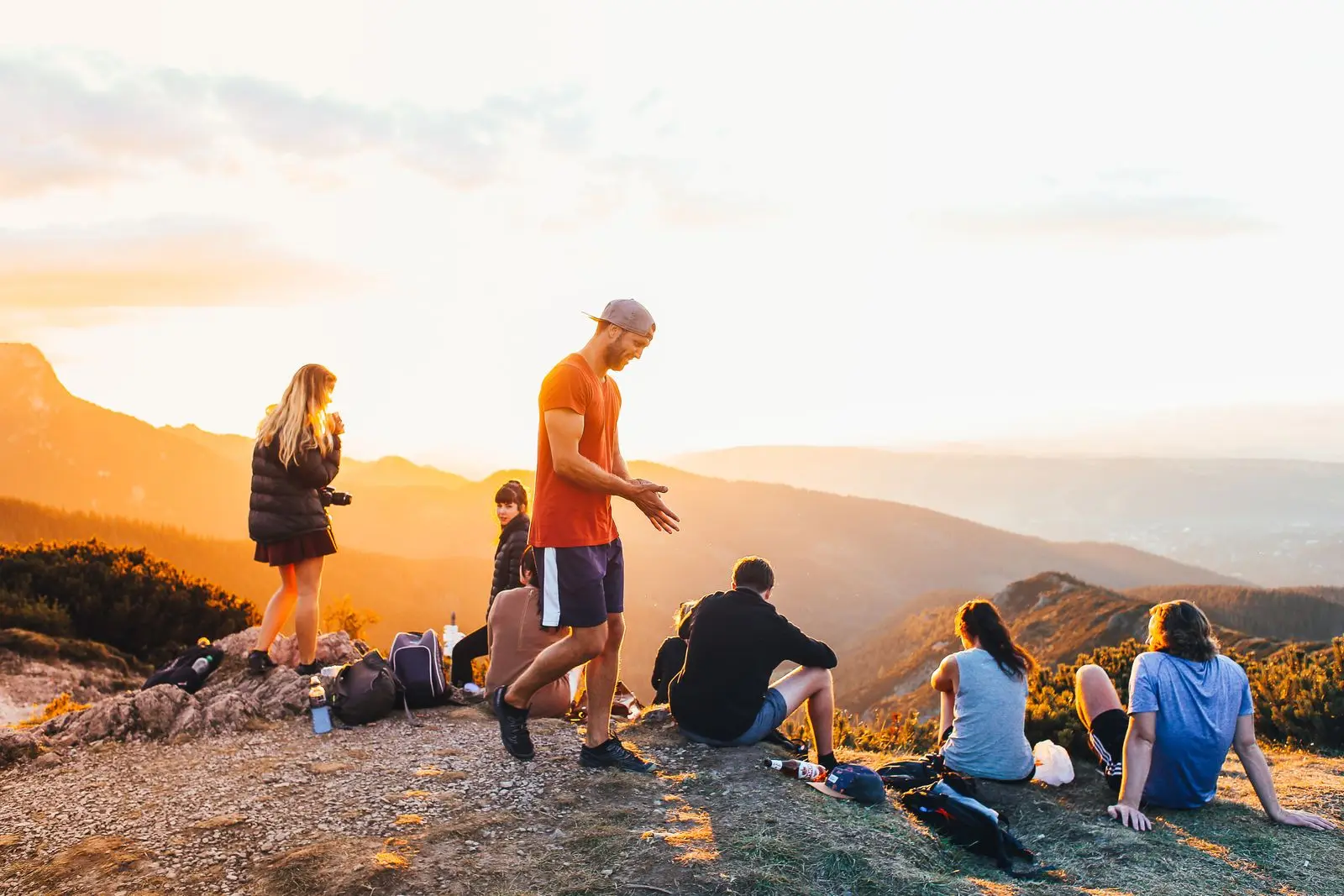 A group of hikers resting and talking on a mountain overlook at golden hour