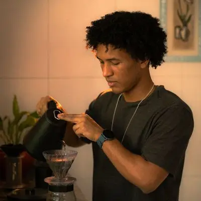 A man pouring water from a gooseneck kettle into a pour-over dripper