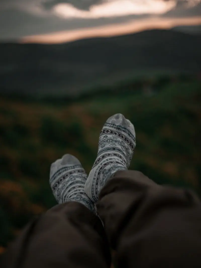 Feet in patterned wool socks propped up against a mountain view at dusk